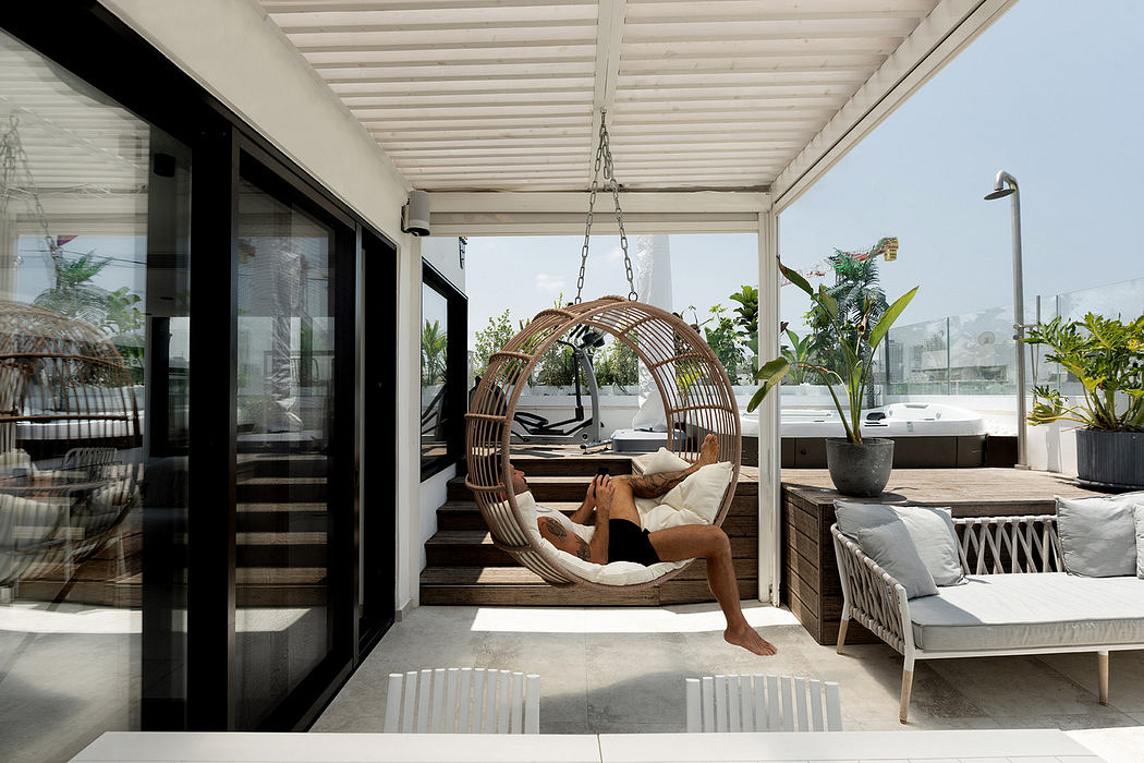 Modern patio with a hanging chair, sofa, and black sliding doors.