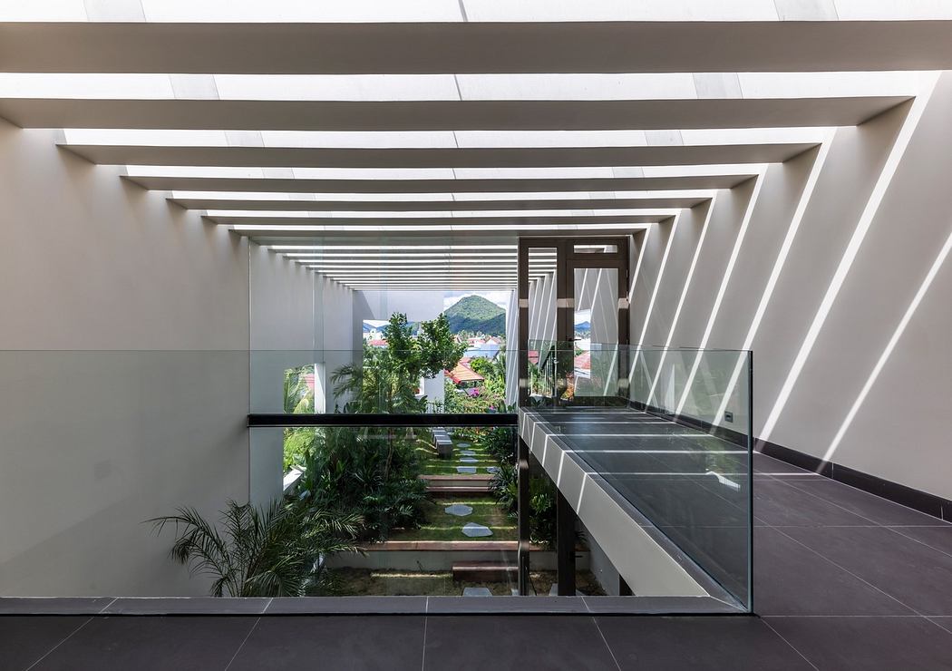 Modern hallway with geometric ceiling and glass balustrades overlooking a garden.