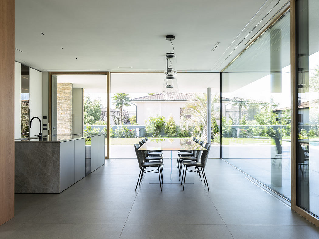 Modern kitchen with dining table set, floor-to-ceiling windows, and garden view