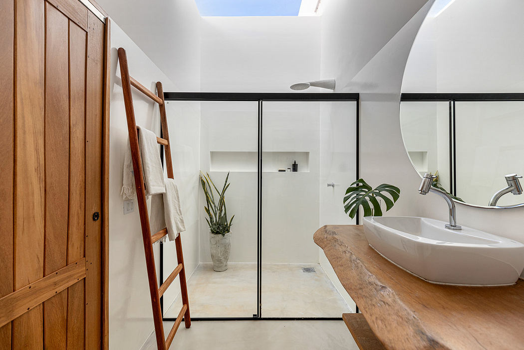 Modern bathroom with wooden accents and glass shower divider.