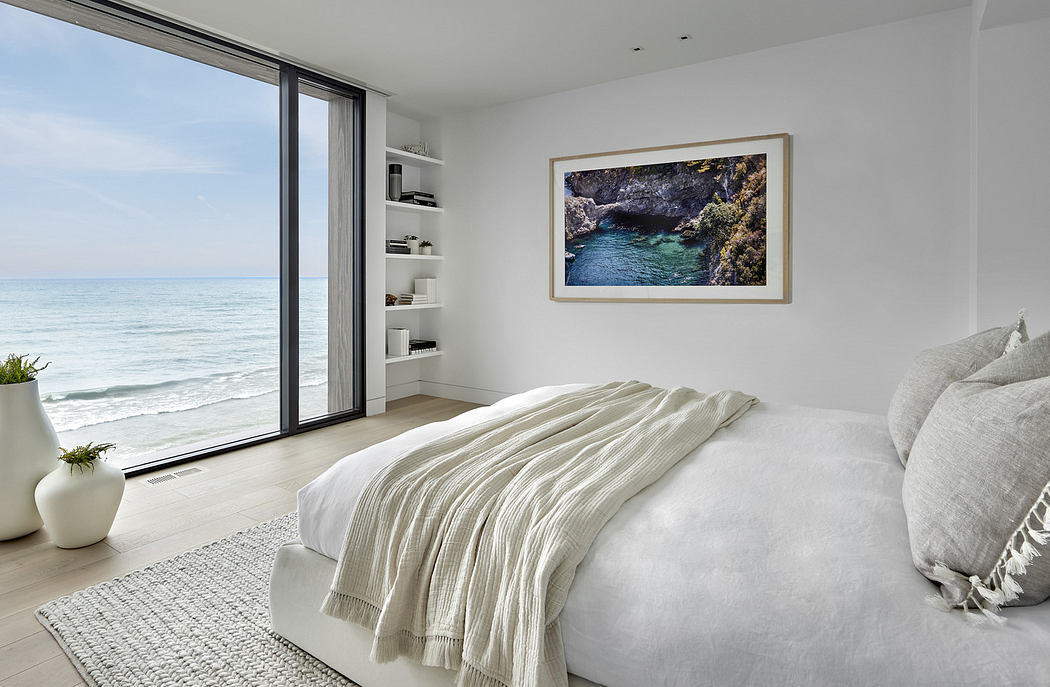 Modern bedroom with ocean view, minimalistic decor, and framed artwork.