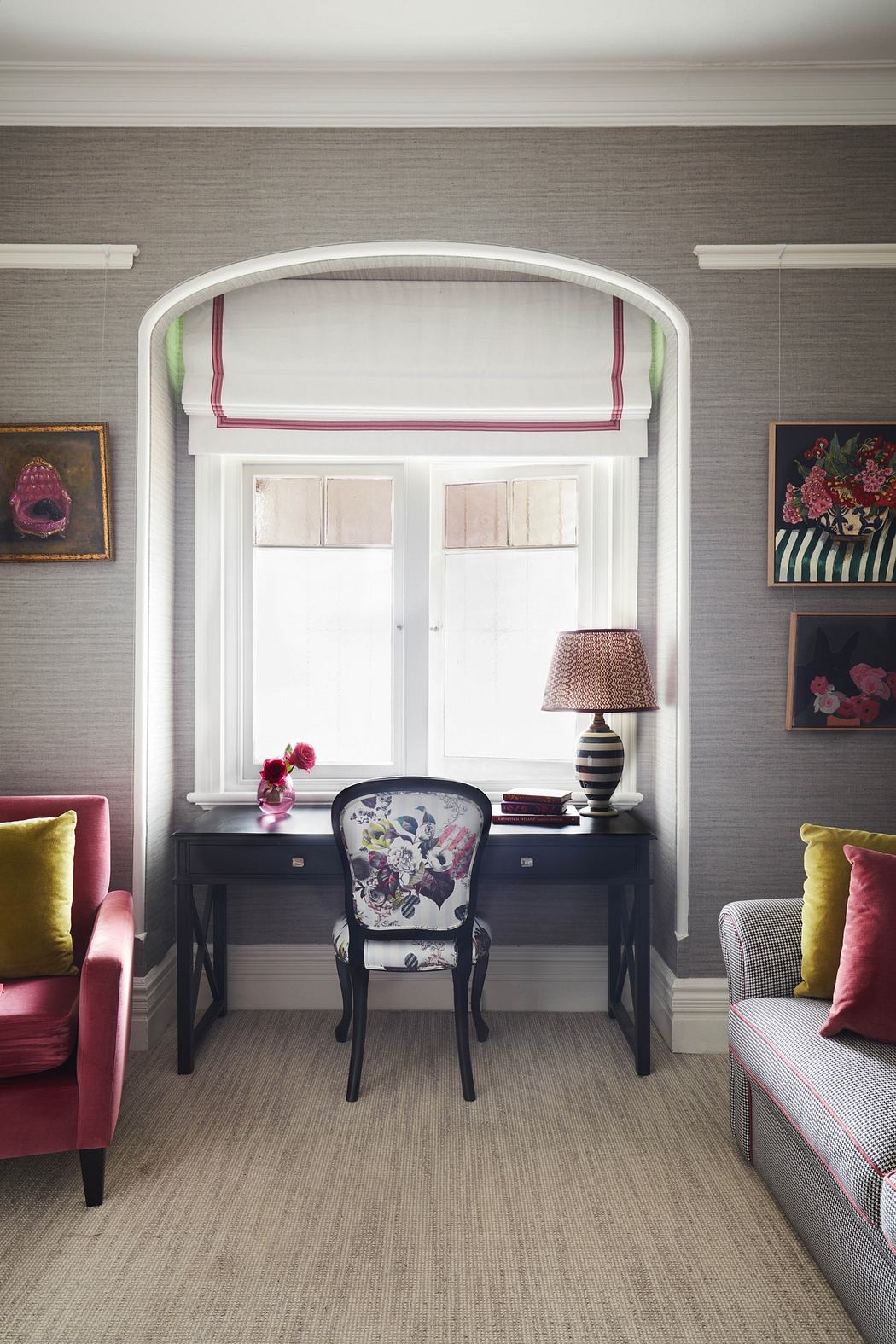 Elegant study nook with arched window, classic desk, and vibrant chairs