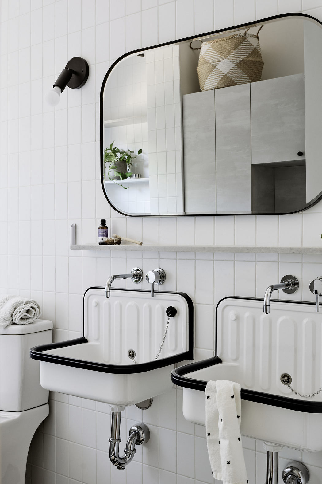 Modern bathroom with white subway tiles and dual wall-mounted sinks.