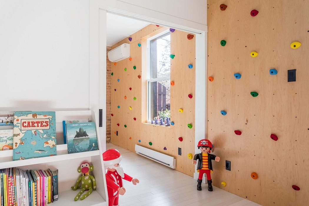 Child's room with a climbing wall feature, toys, and bookshelf.