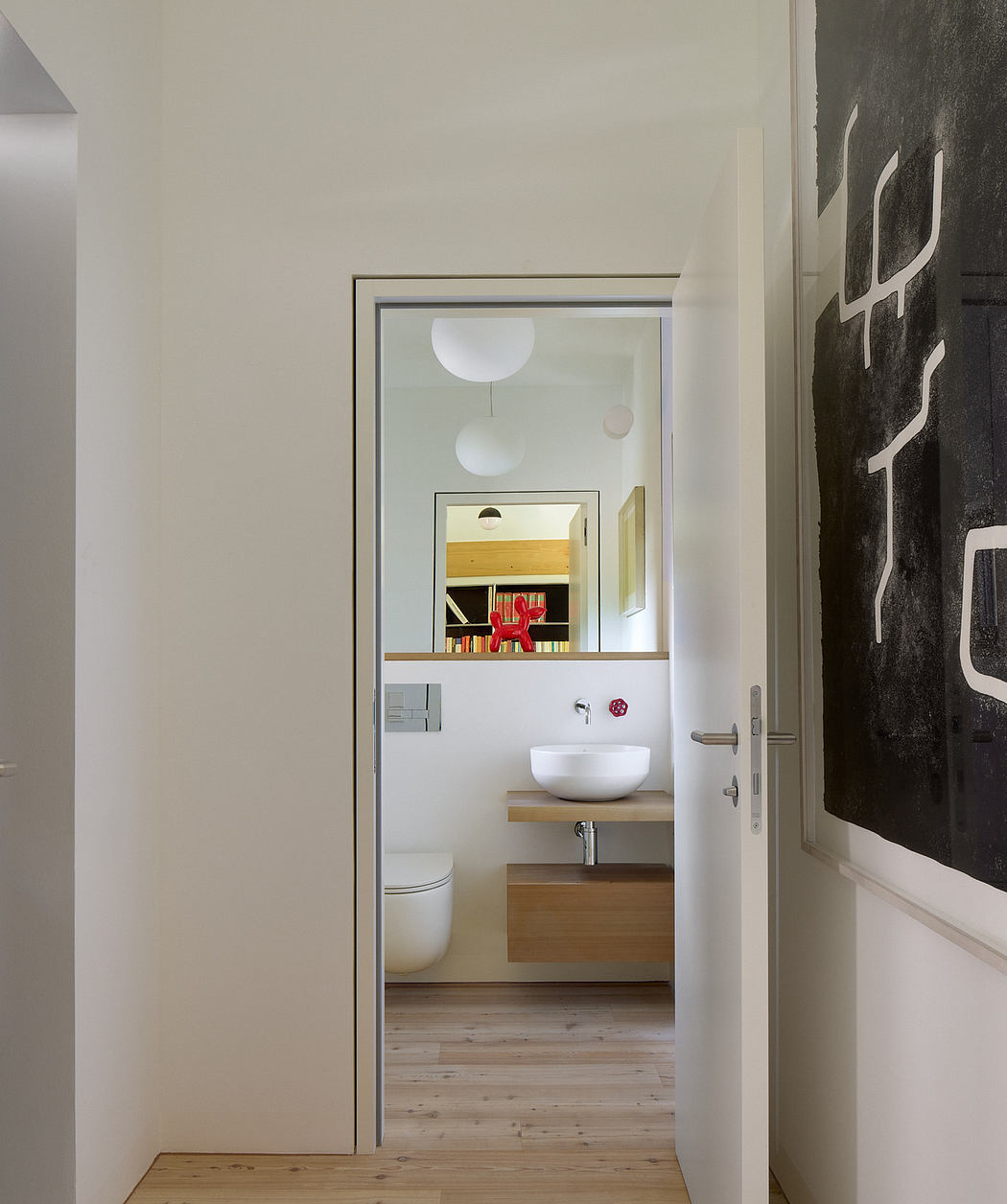 Modern bathroom viewed through an open door with minimalist decor.