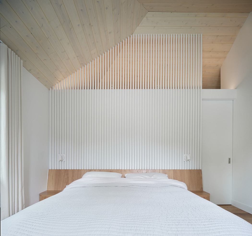 Minimalist bedroom with slatted wood walls and angled ceiling.