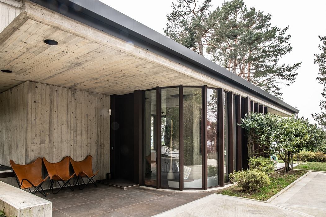 Modern house with concrete and glass facade and butterfly chairs.