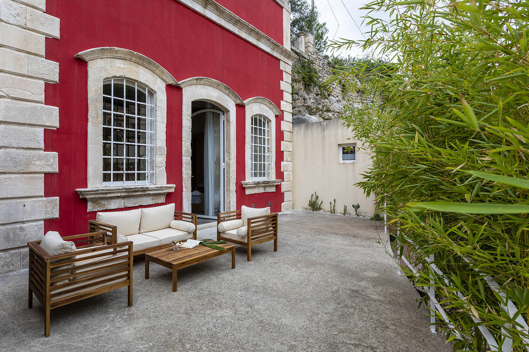 Elegant patio with red walls, white windows, and wooden seating.