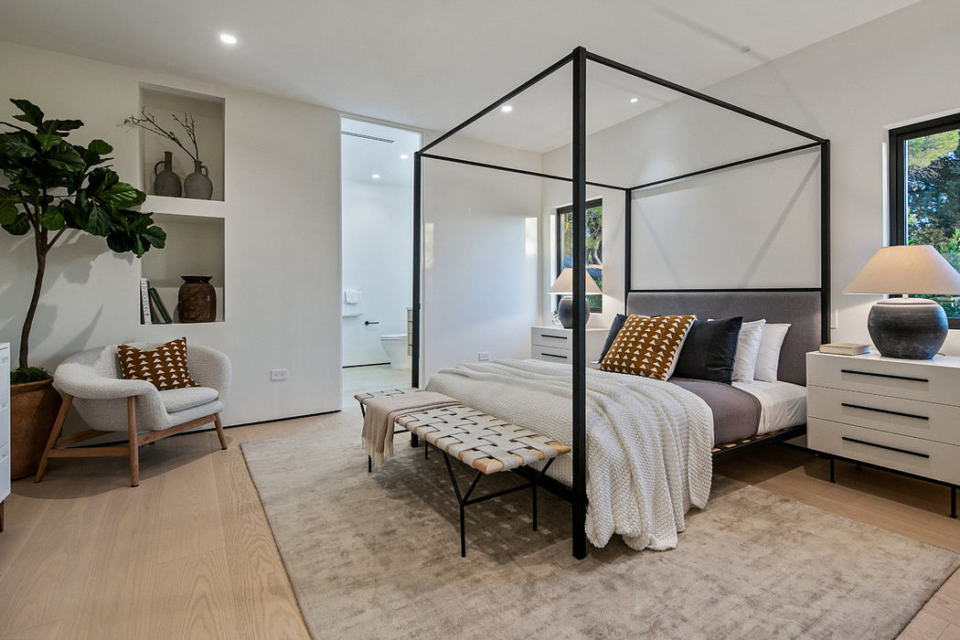 Modern bedroom with a four-poster bed, minimalist furniture, and large windows.