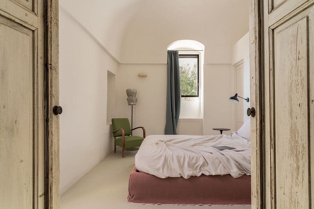 Serene bedroom with arched window, vintage door, and minimalist decor.