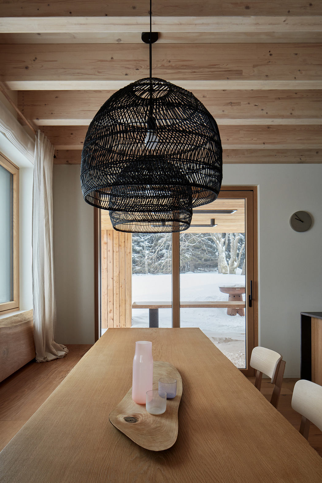 Modern dining room with large woven pendant light and wooden details.