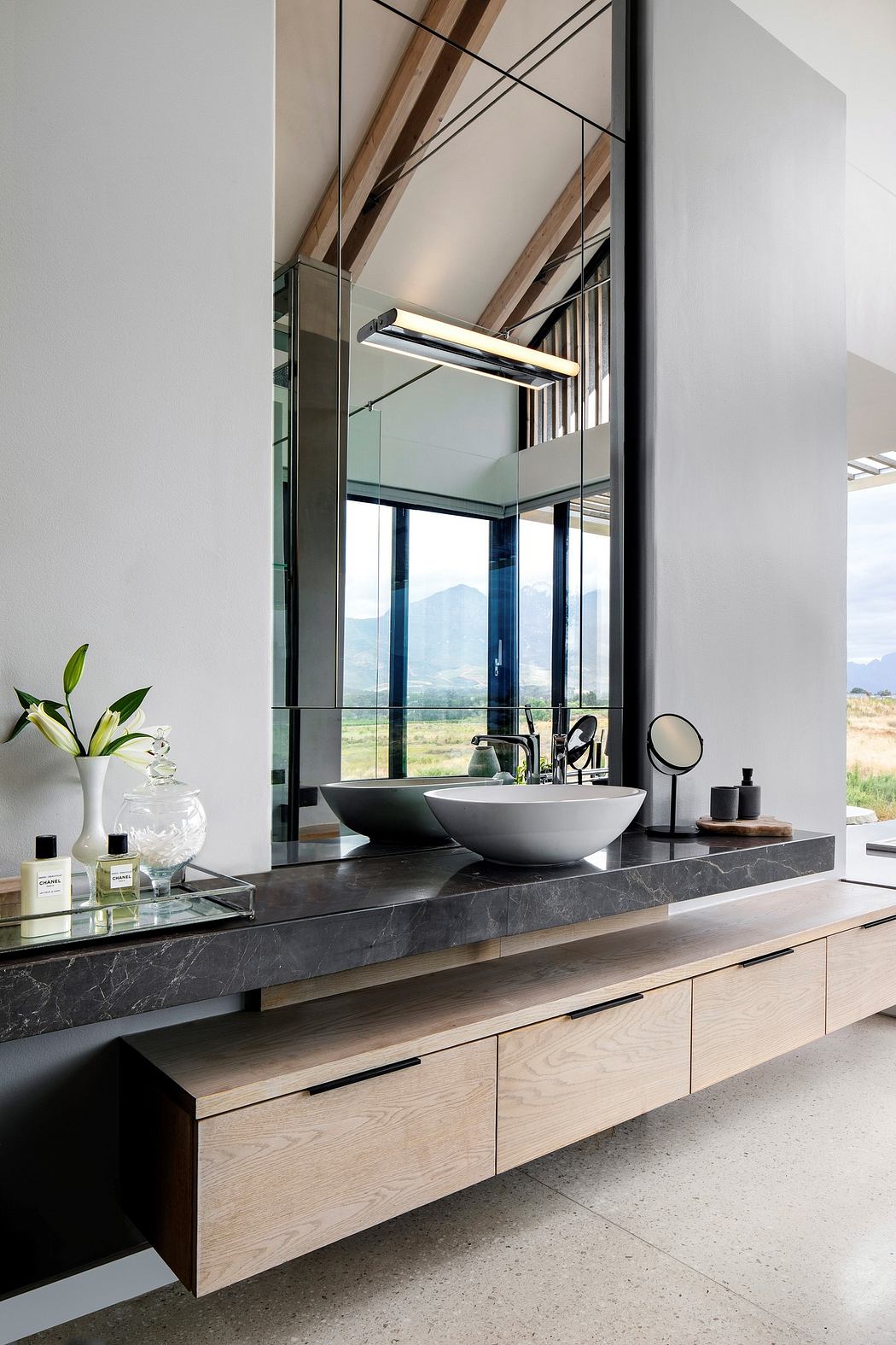 Modern bathroom vanity with a large mirror and mountain view.