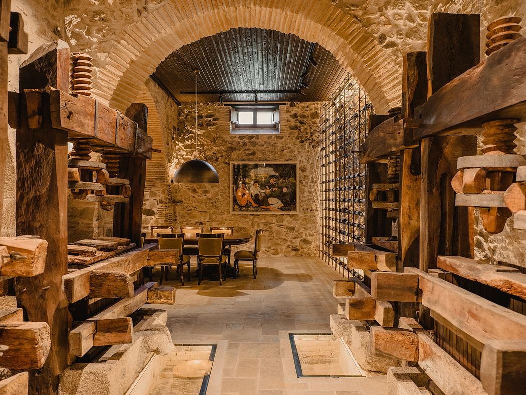 Rustic wine cellar interior with stone walls and wooden racks.
