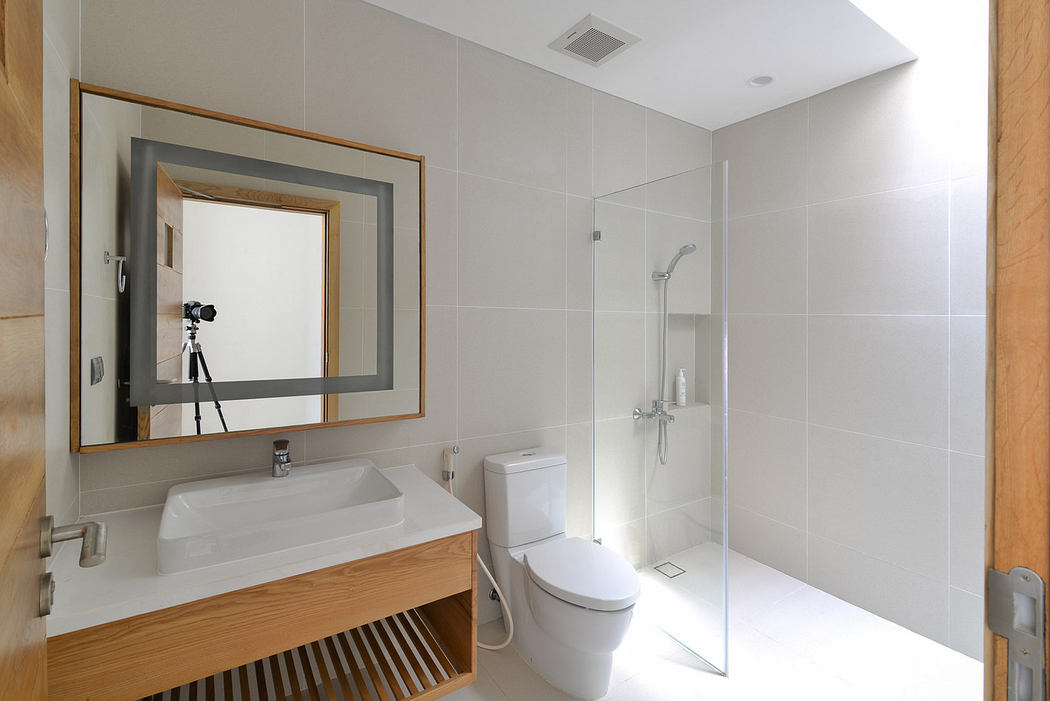 Modern bathroom with white tiles, glass shower, and mirrored sink vanity.