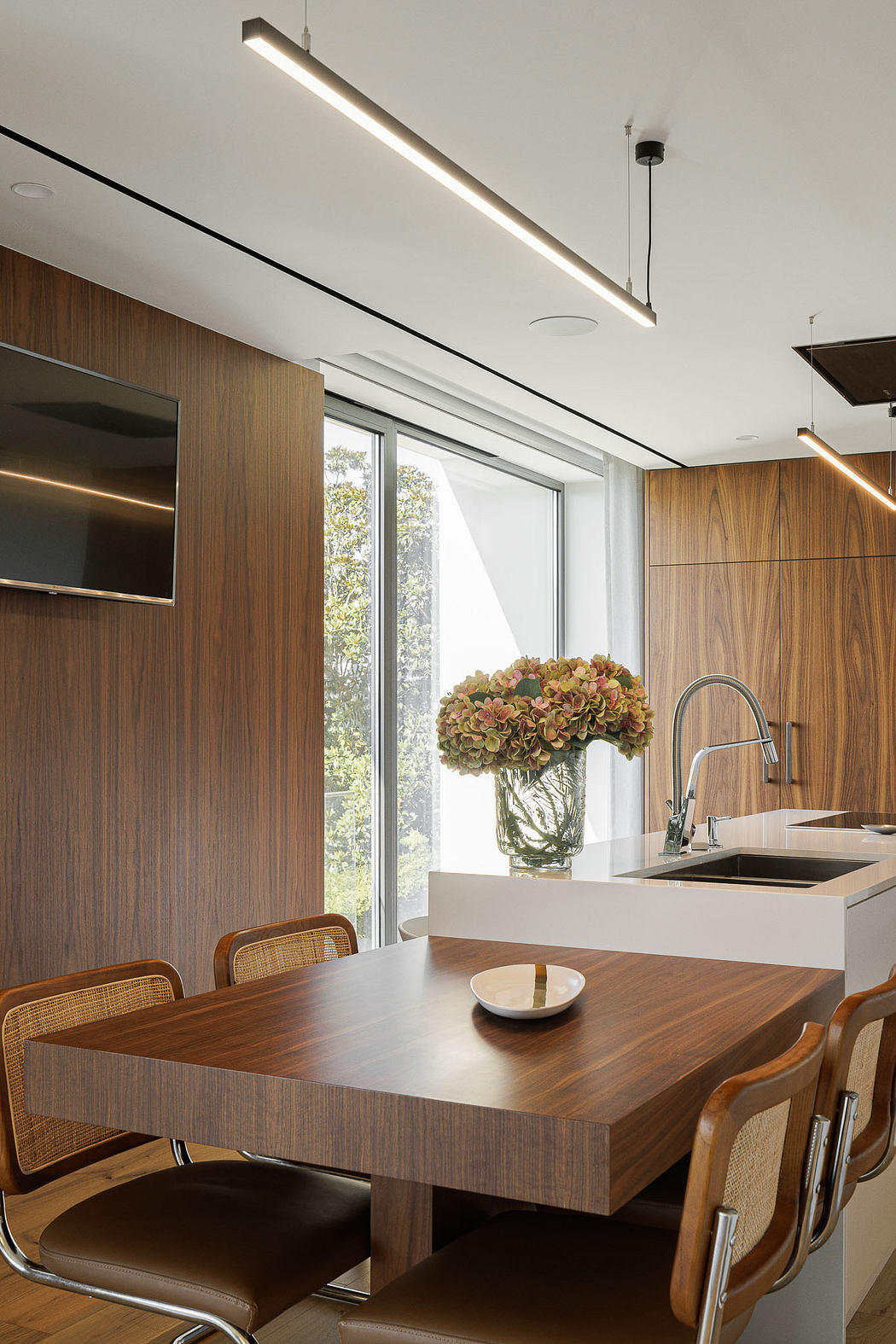 Modern kitchen with wooden finishes and a dining table with flowers.