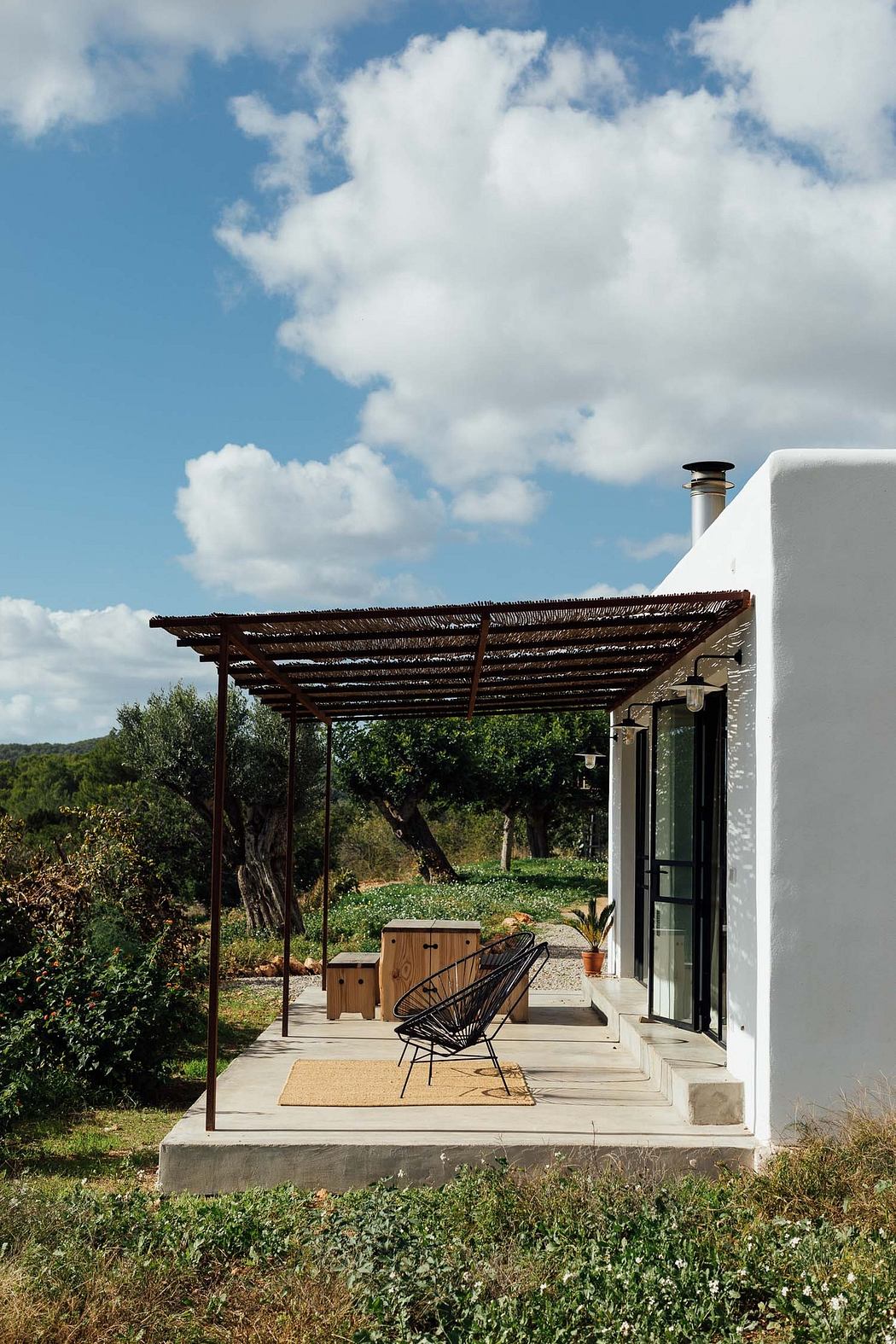 White minimalist house with patio and pergola against a natural backdrop.