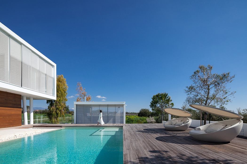 Modern home with pool, deck, and loungers under clear sky.