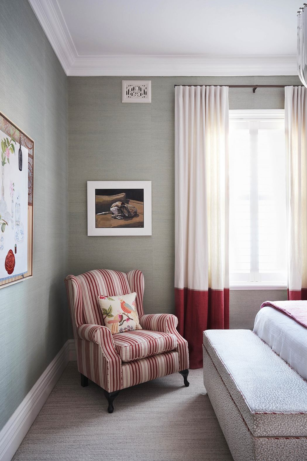 Elegant bedroom corner with striped armchair, artwork, and dual-tone curtains.