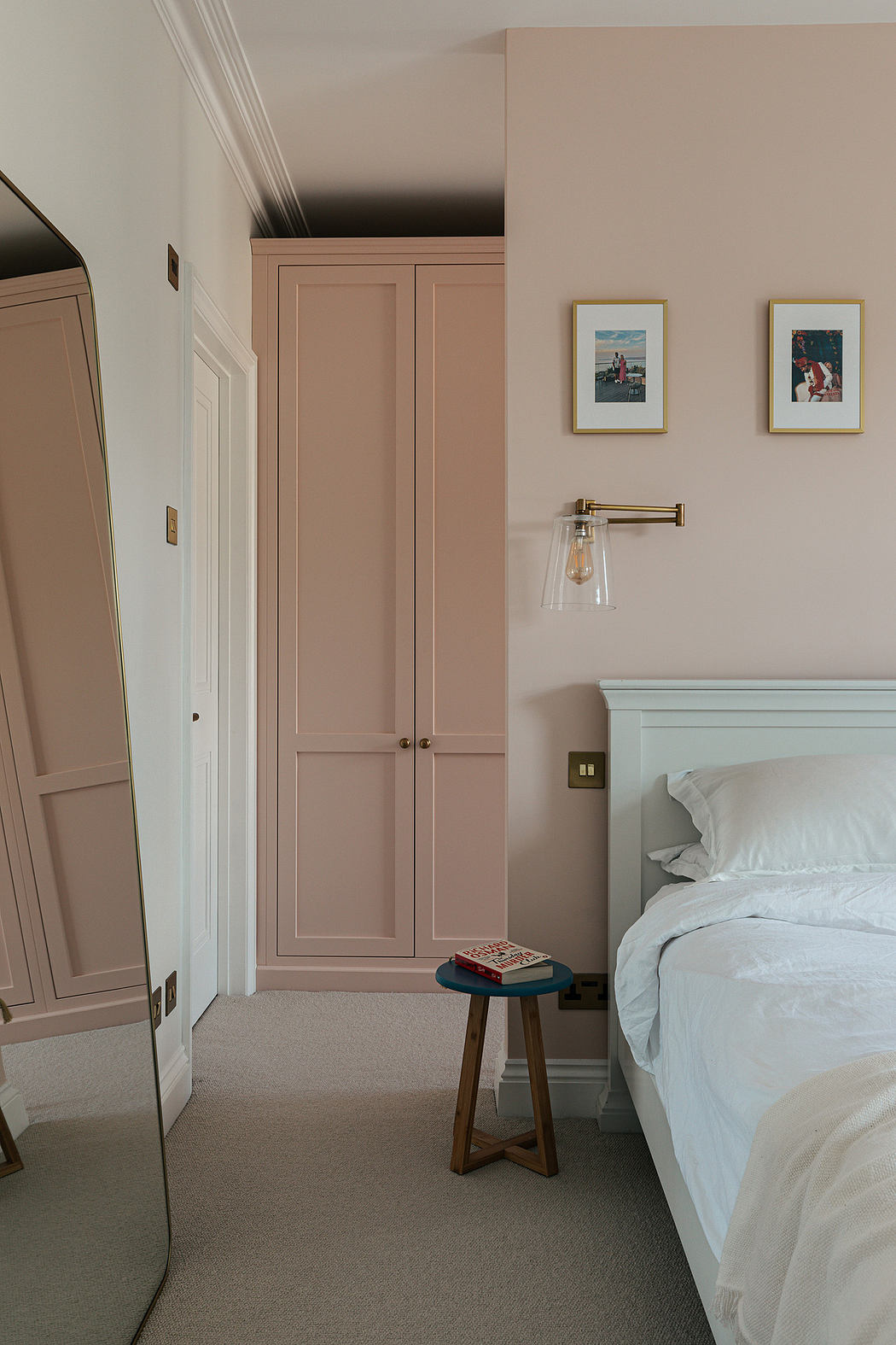 Elegant pink bedroom interior with classic wooden door and wall art.