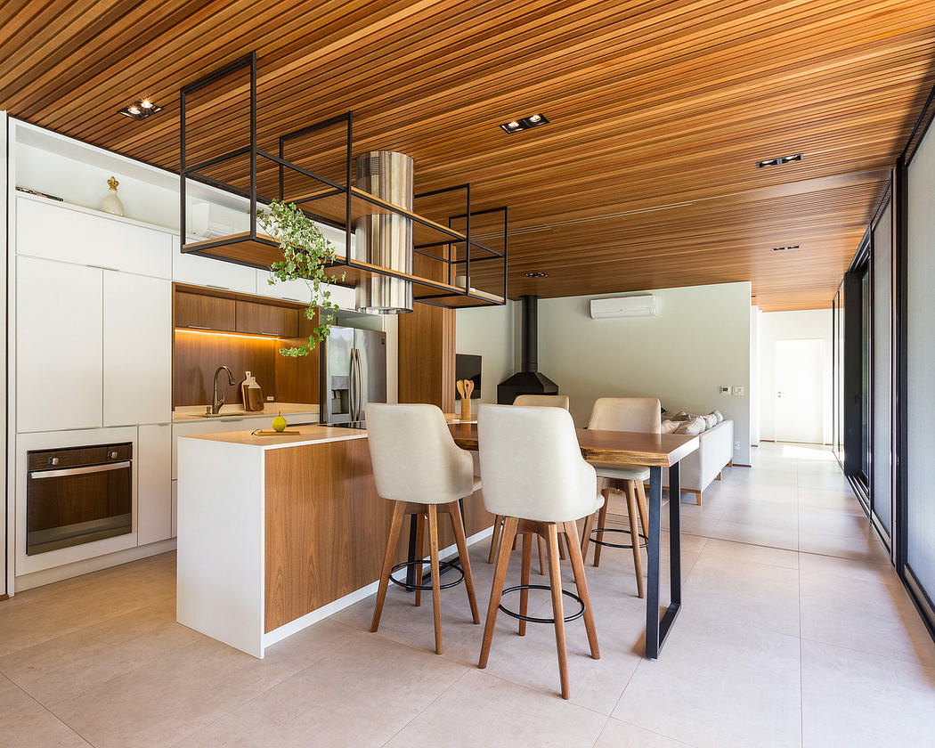 Modern kitchen interior with wooden finishes and sleek bar stools.