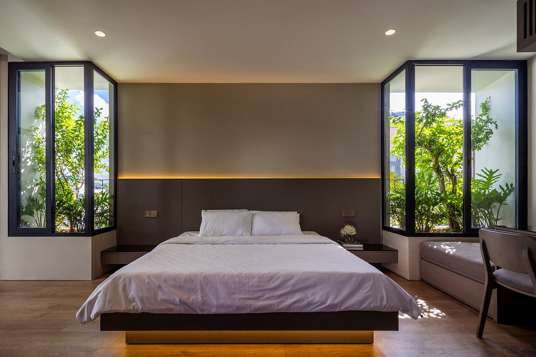 Modern bedroom with large bed, floor-to-ceiling windows, and garden view.