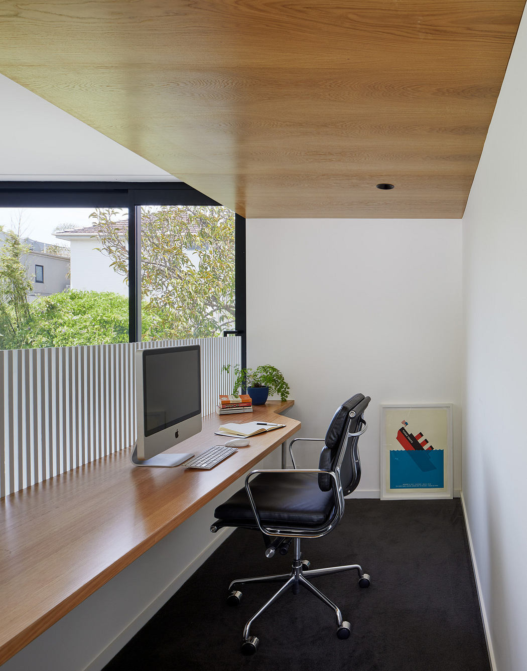 Modern home office with wooden desk, chair, and slatted window details.