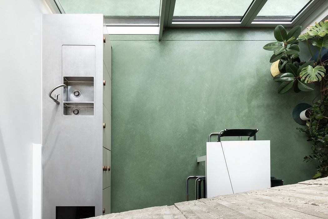 Modern bathroom with green walls, skylight, and minimalist fixtures.