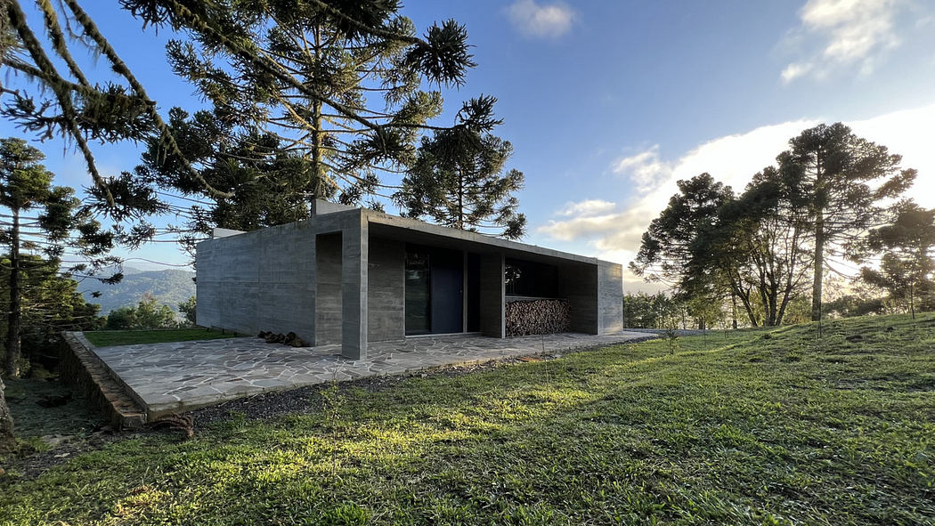 Modern minimalist house with large windows, nestled in a grassy hillside.