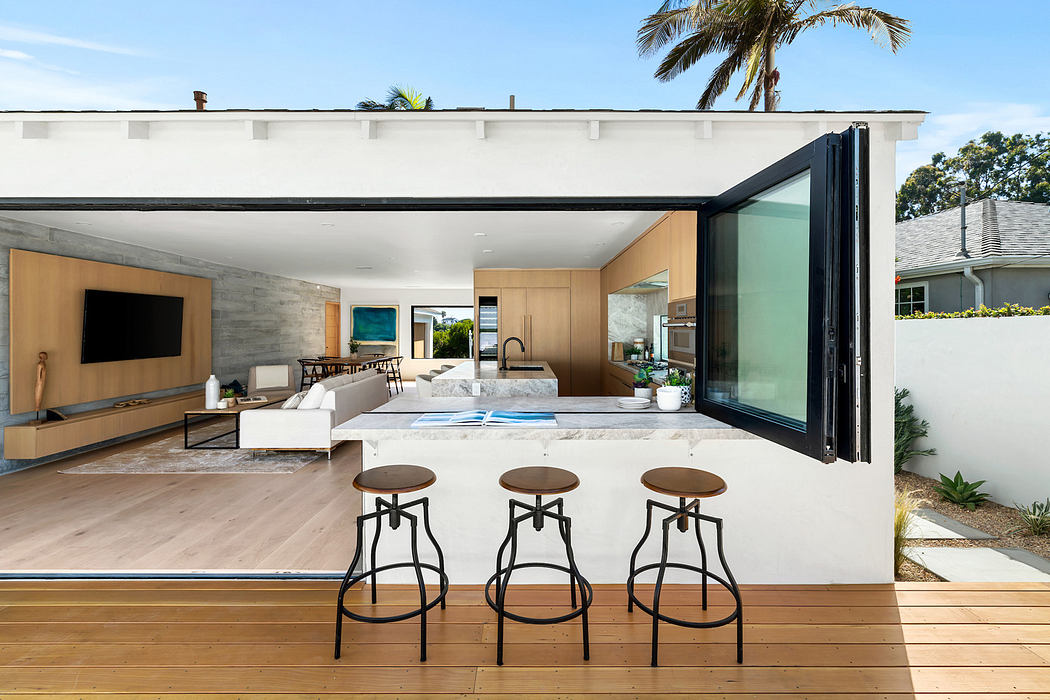 Modern indoor-outdoor kitchen with bar stools and open layout.