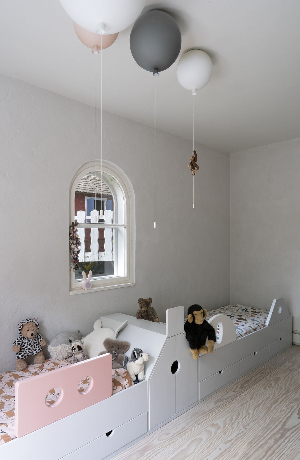 Minimalist children's room with a whimsical bed and balloon ceiling lights.