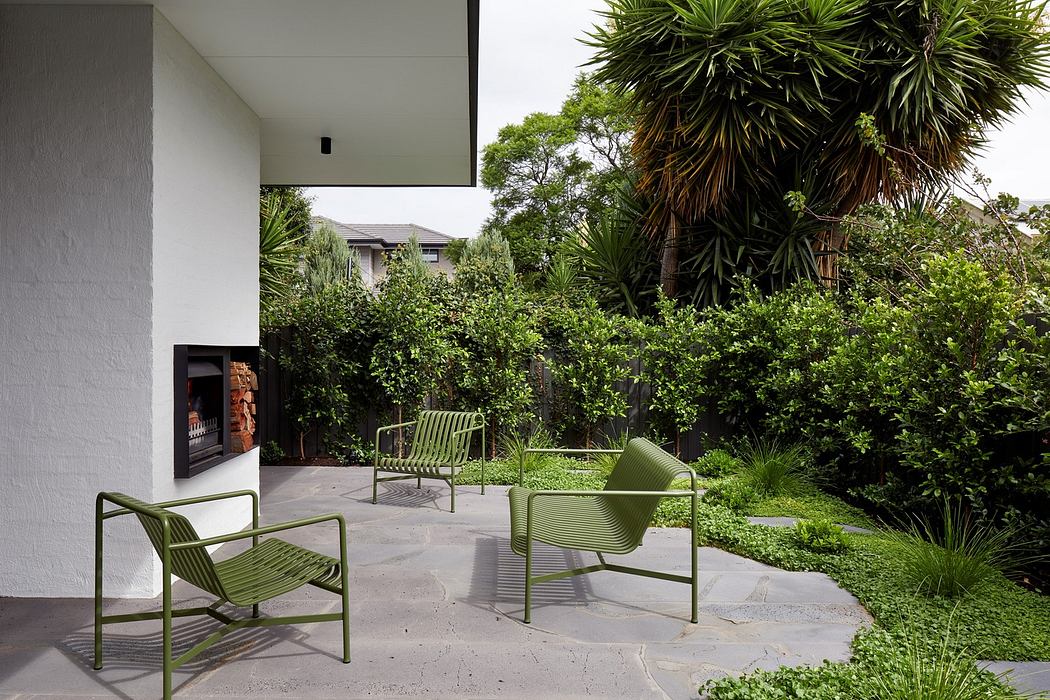 Modern patio with green chairs, fireplace, and lush garden.