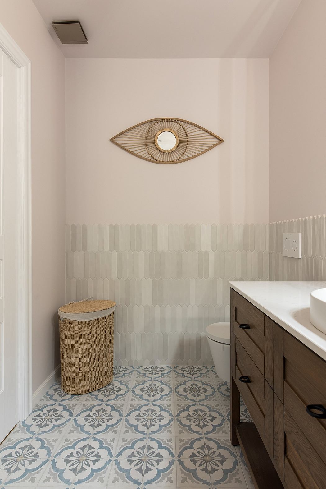 Modern bathroom with patterned floor tiles and decorative wall sconce.