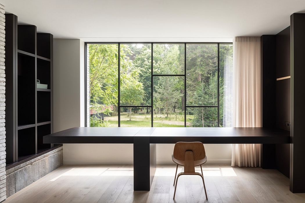 Modern room with large window overlooking trees, minimalist furniture, and neutral tones.