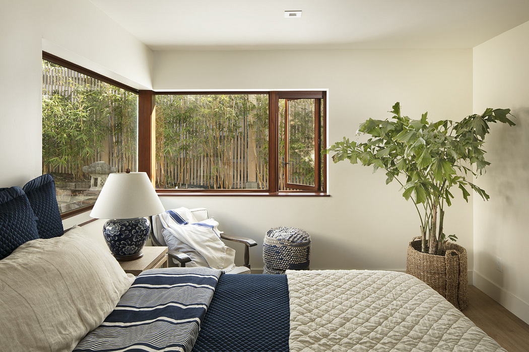 Modern bedroom with large window, neutral tones, and potted plant.