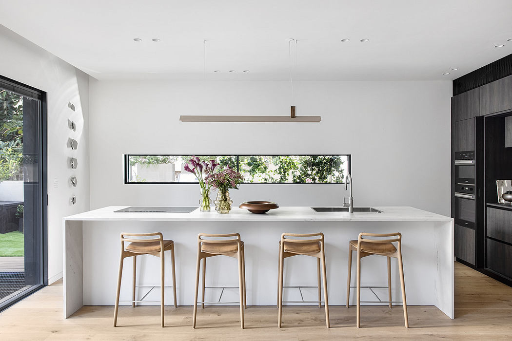 Modern kitchen with white island, wooden stools, and pendant lighting.
