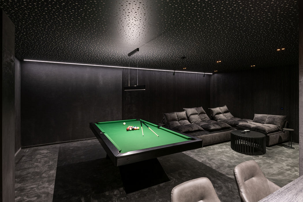 Modern game room with a green pool table, dark walls, and textured ceiling.