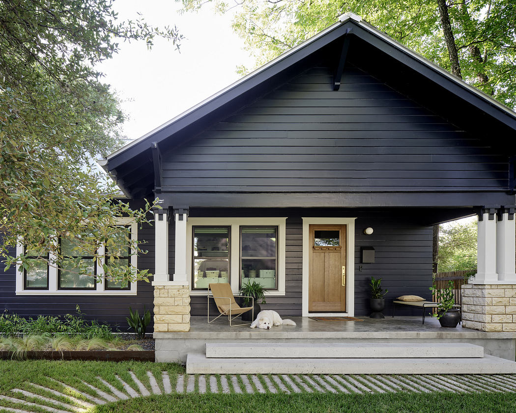 Modern black house with white trims, stone pillars, and a sleeping dog on