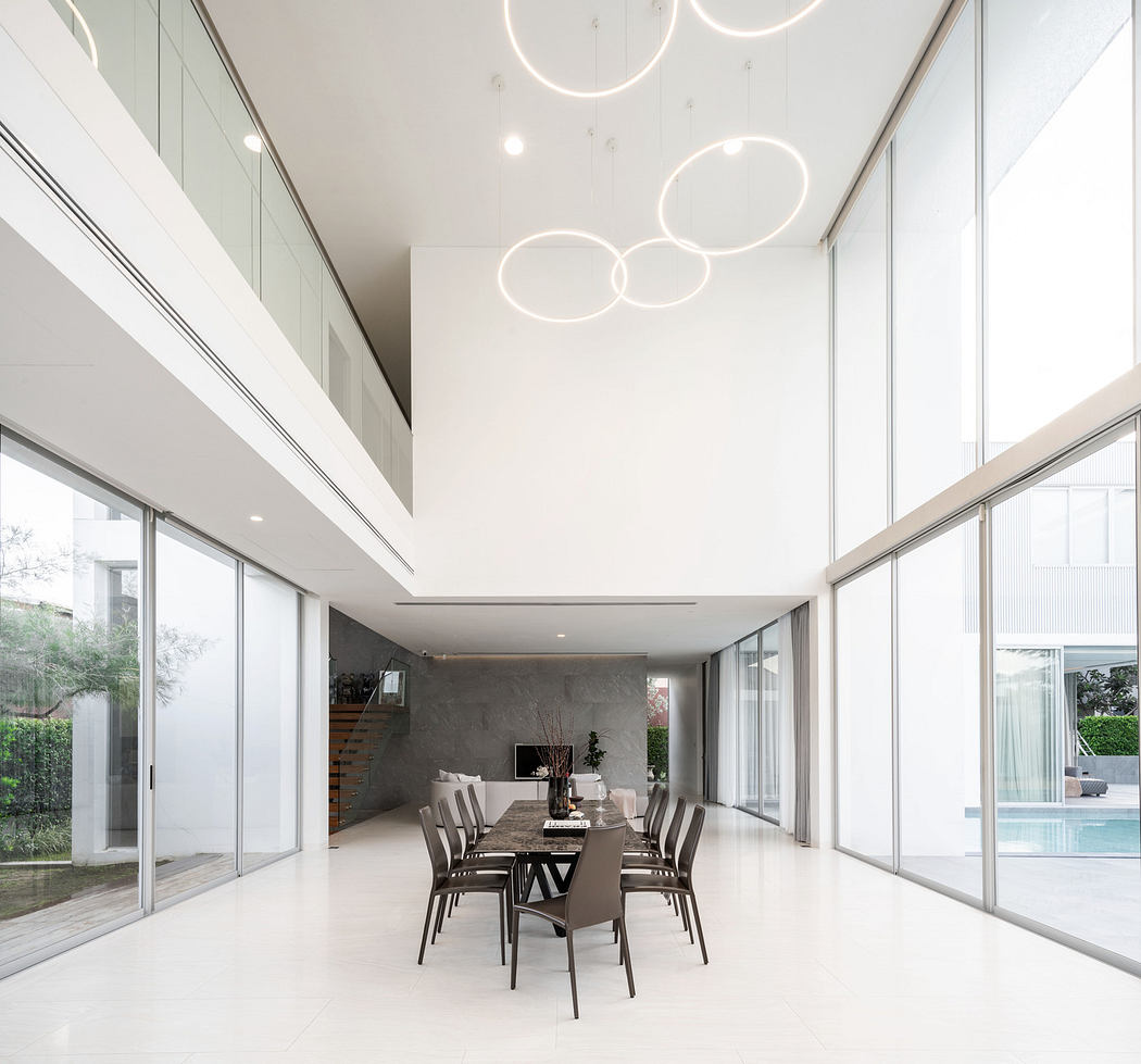 Modern minimalist dining area with ring-shaped lights and glass walls.