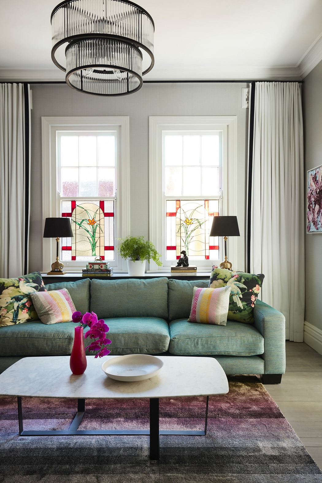 Elegant living room with a turquoise sofa, modern chandelier, and vibrant accents