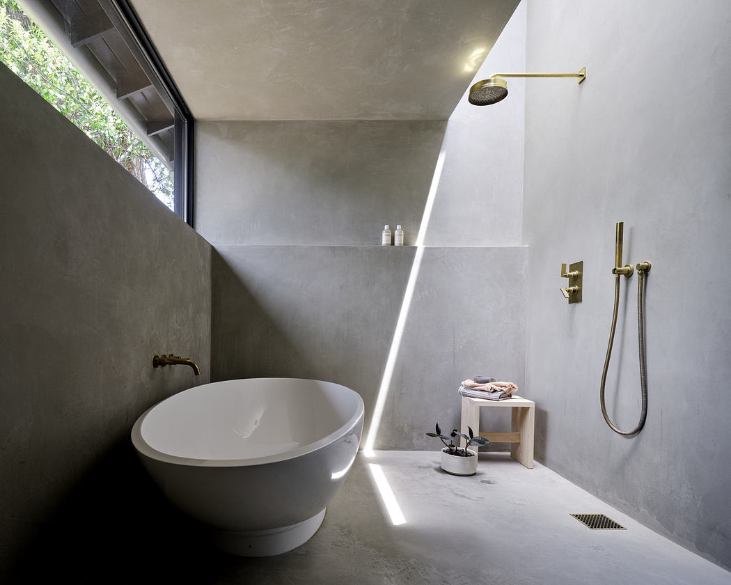 Modern bathroom with a freestanding tub, brass fixtures, and skylight