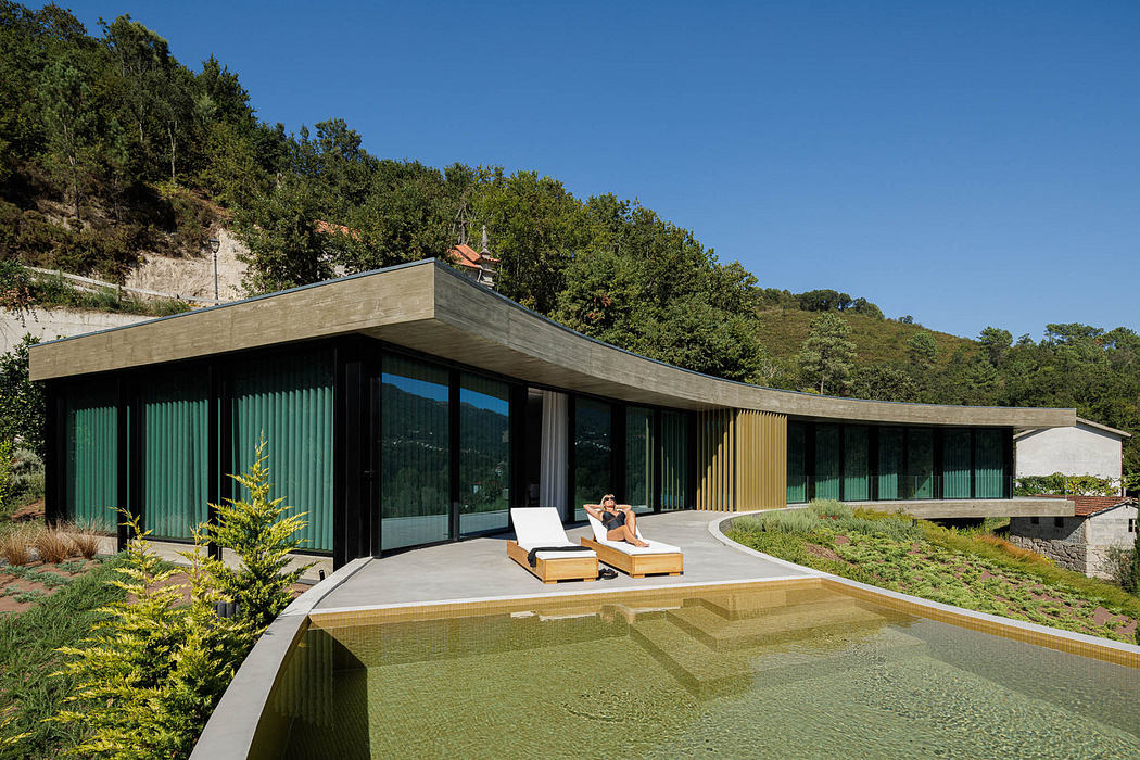 Modern curved house with large windows and an infinity pool.