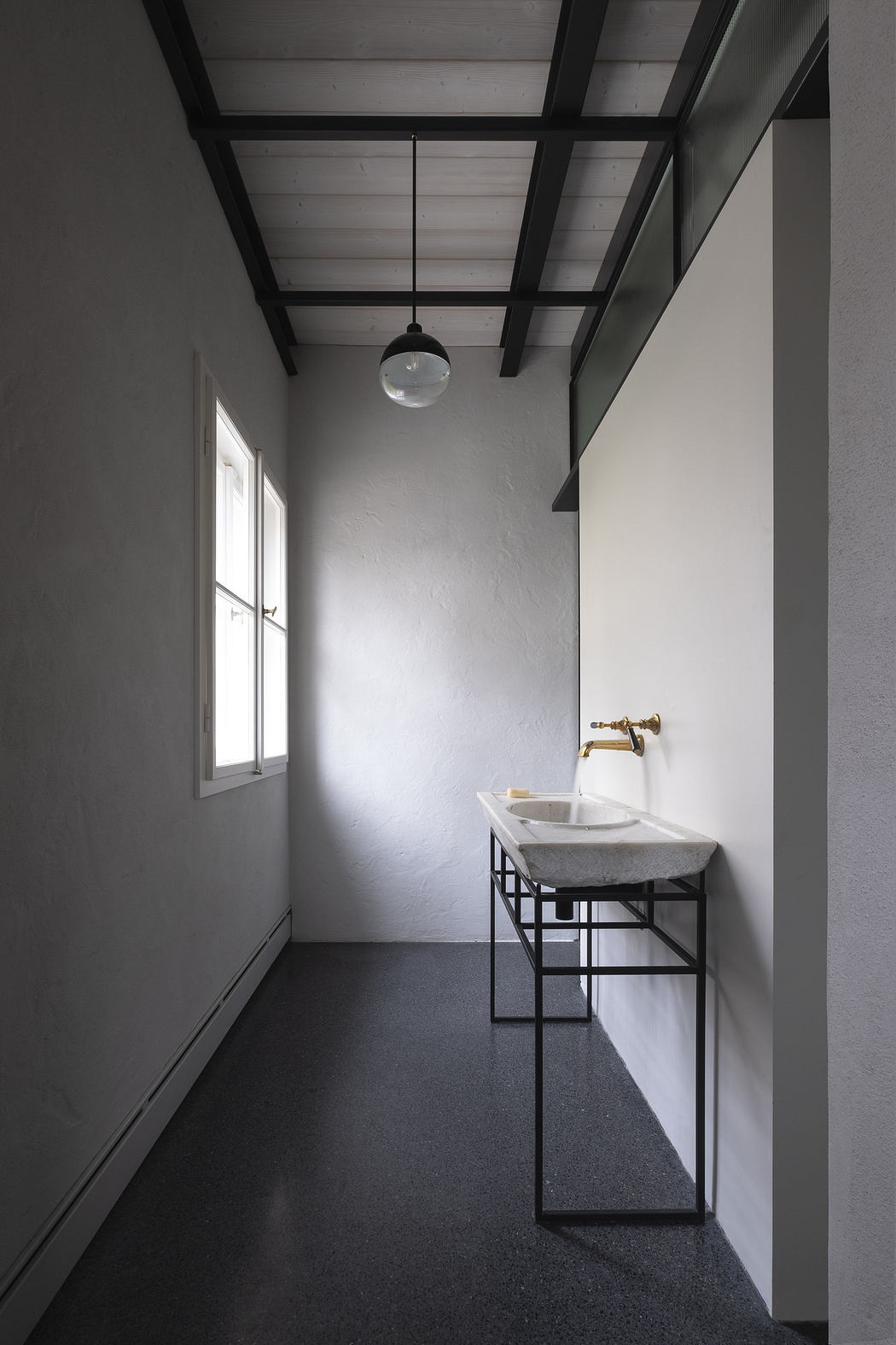 Minimalist interior with a sleek sink, dark floor, white walls, and exposed