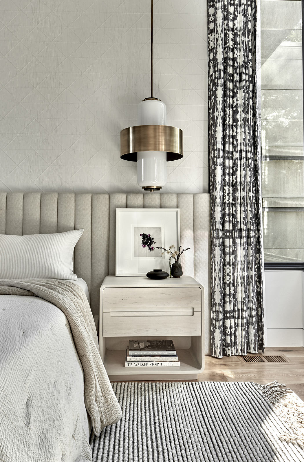 Modern bedroom corner with elegant bedside table, pendant lamp, and window with curtains.
