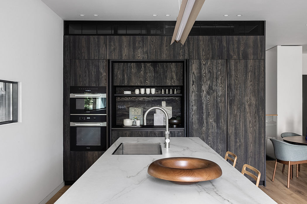 Modern kitchen with dark wood cabinetry and marble countertops.