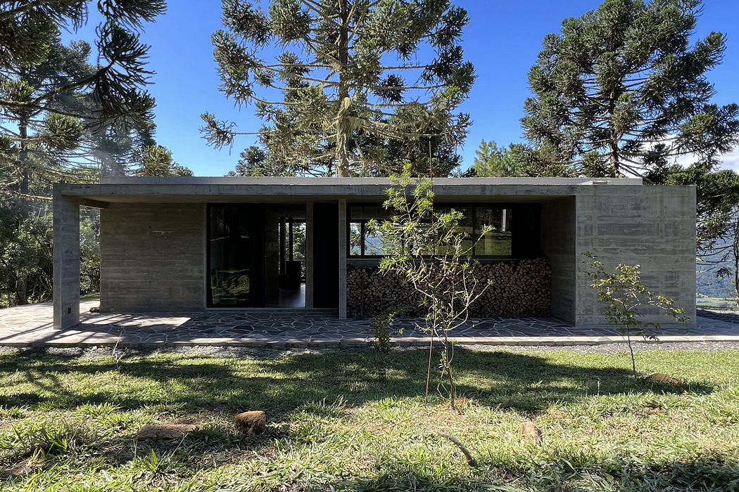 Modern concrete house with large windows surrounded by trees.