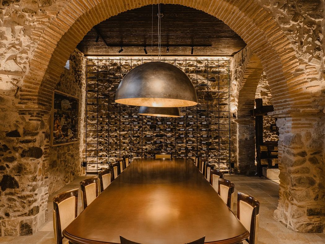 Rustic stone-walled room with a long wooden table and oversized dome pendant