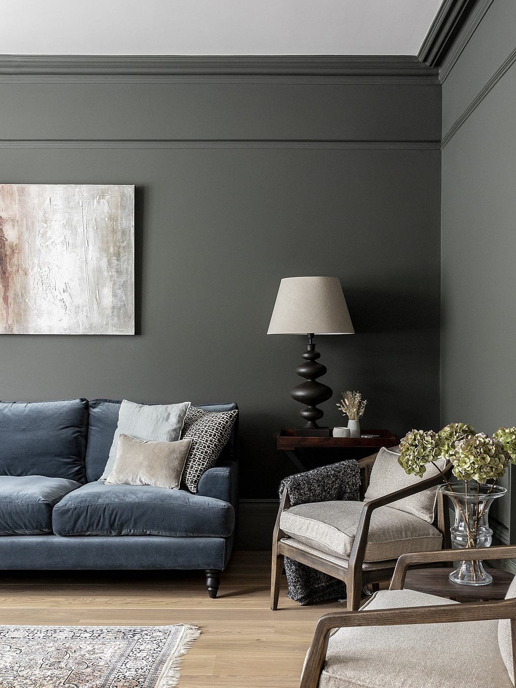 Elegant living room with a navy sofa, wooden furniture, and grey walls.