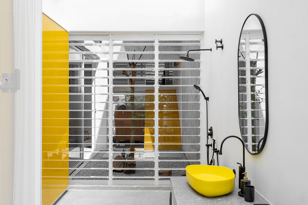 Modern bathroom with yellow basin, white walls, and glass divider.