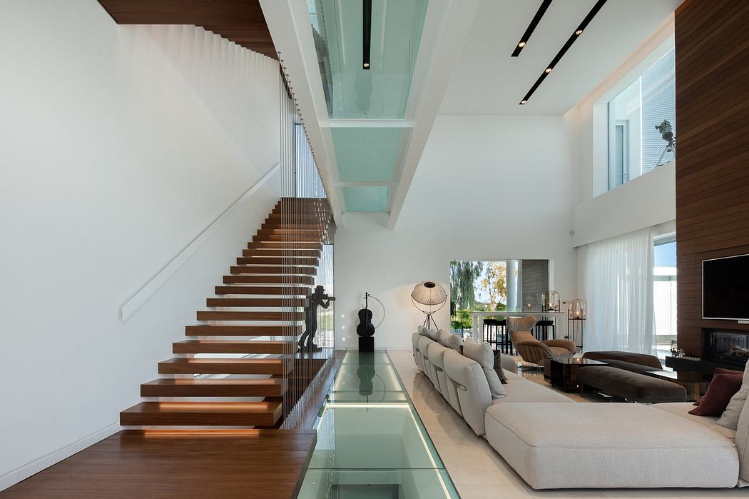 Modern living room with floating staircase and glass floor detail.