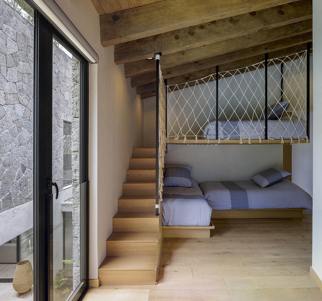 Modern room with wooden stairs leading to a loft bed, stone wall, and large